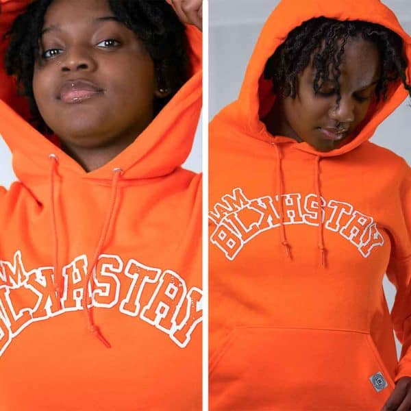 two pictures of a College age female model wearing orange I am black history hoodie with white letters